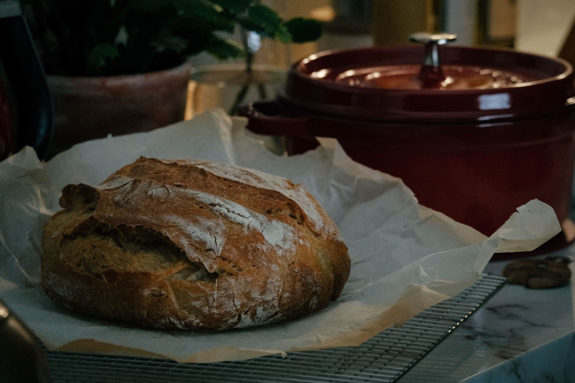 A rustic loaf of bread cooling on a wire rack in a kitchen