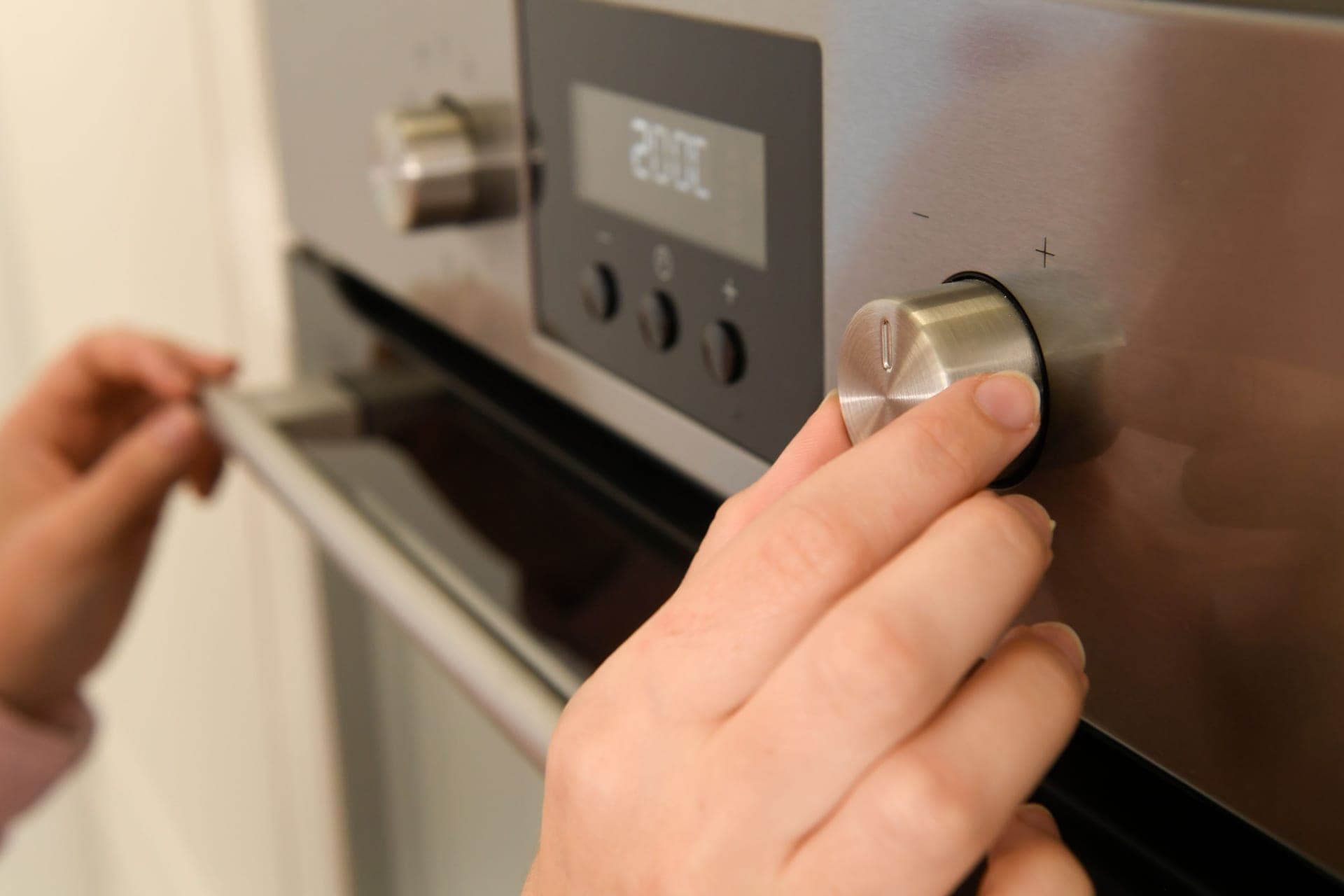 A hand turning the temperature dial on an oven